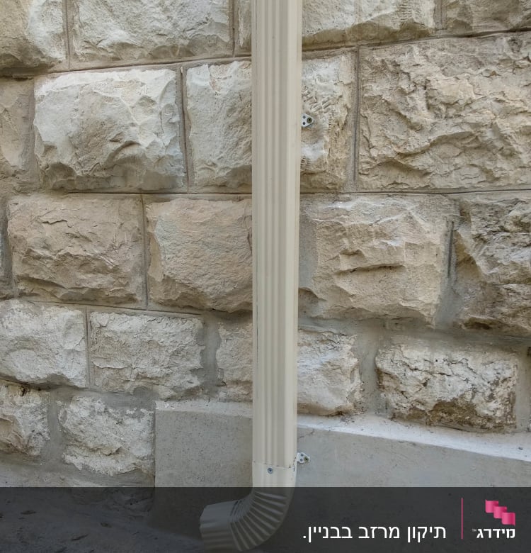 מרזב לבן מחובר לקיר אבן